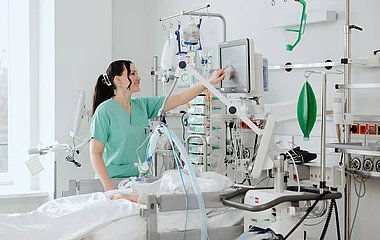 Pflegekraft versorgt eine Patientin auf einer Intensivstation.