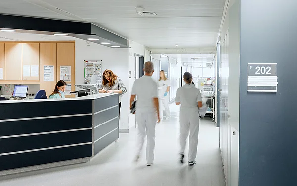 Zwei Pflegekräfte gehen durch einen hellen Krankenhausflur.