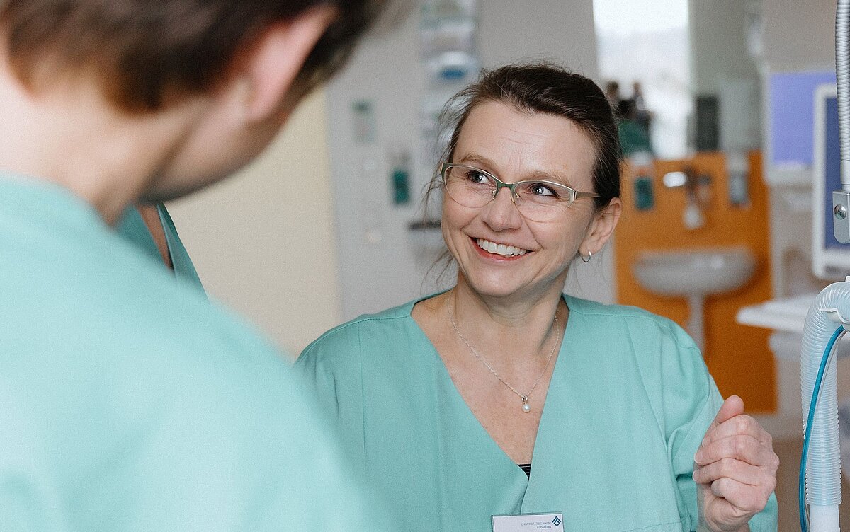 Pflegekraft im Gespräch mit Kollegen im Zentrum für Intensivtherapie