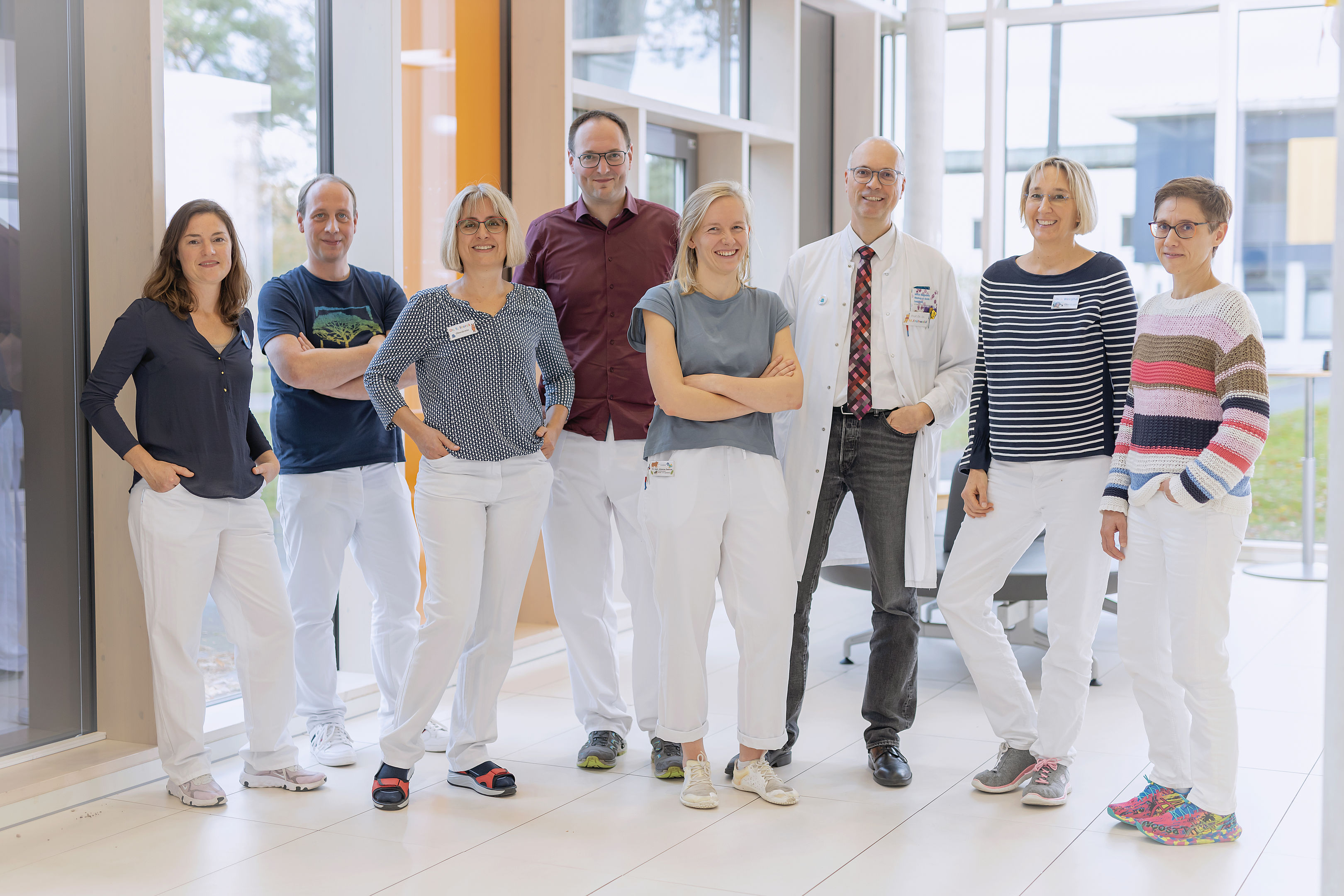 Ein Team aus acht Forschern steht im Foyer und lächelt in die Kamera.